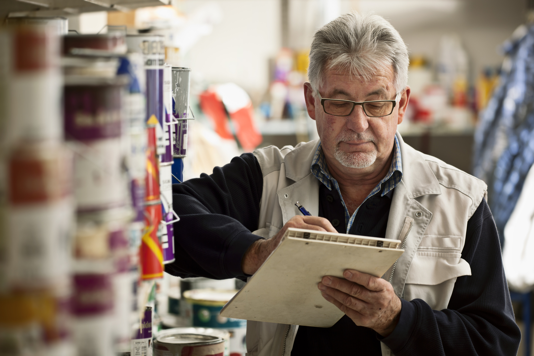 Business owner takes inventory of paint cans at a hardware store