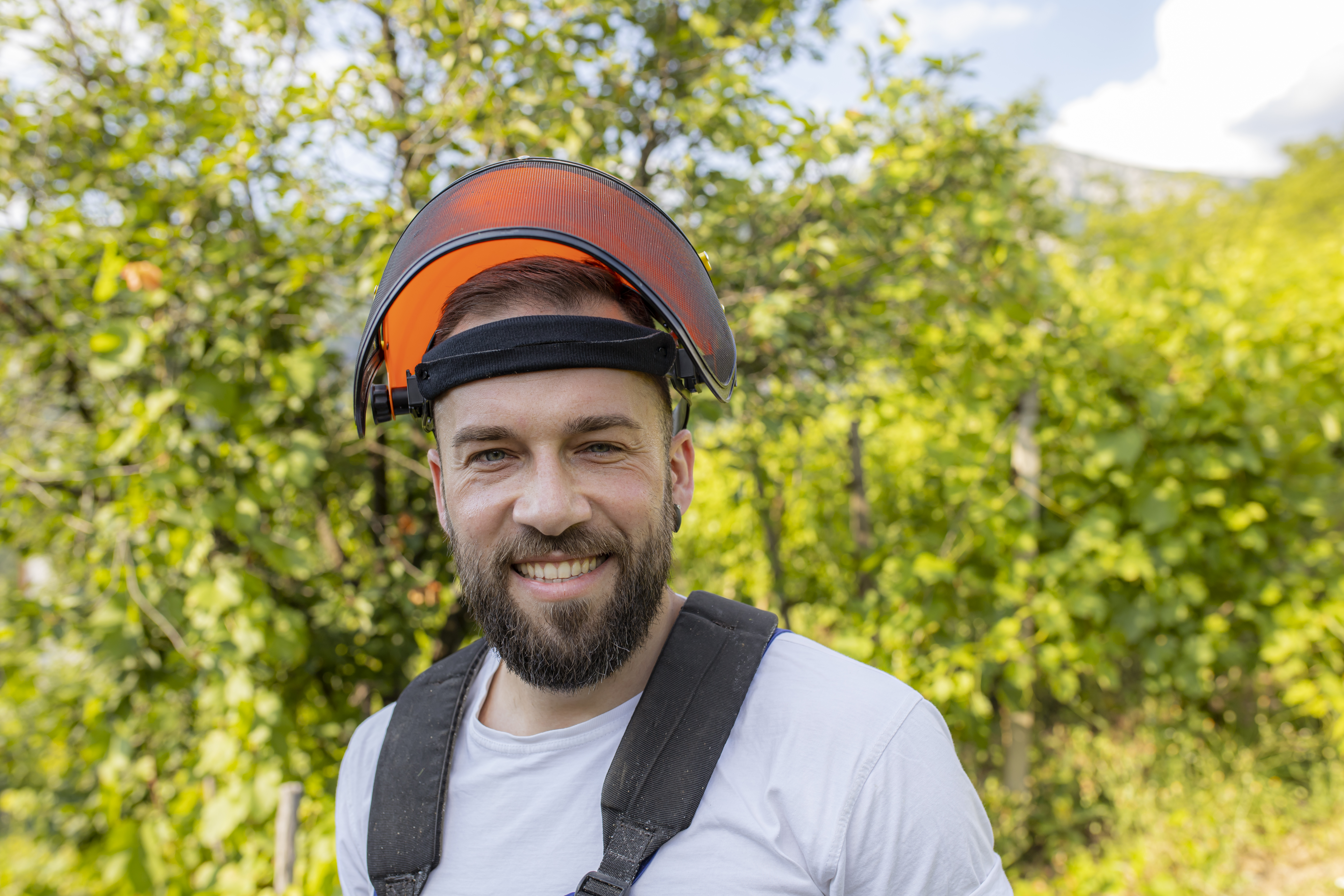 man with heavy duty helmet and face protector smiling at camera